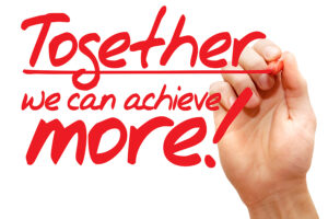 ALT text: A hand writing the motivational phrase "Together we can achieve more!" in red marker, emphasizing the power of teamwork and collaboration to reach greater success.