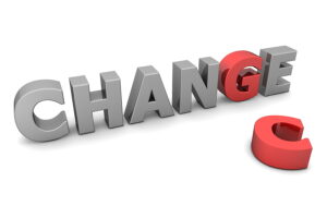 The word 'CHANGE' in bold, metallic 3D letters, with the letter 'C' separated and placed on the ground in red, symbolizing transformation and evolution.